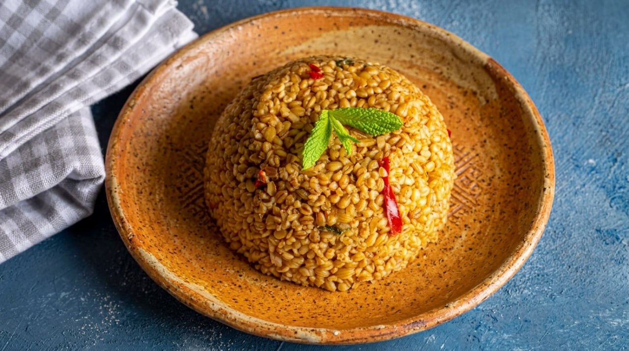 Siyez bulgur pilavı, taze nane yaprakları ve kırmızı biberle süslenmiş