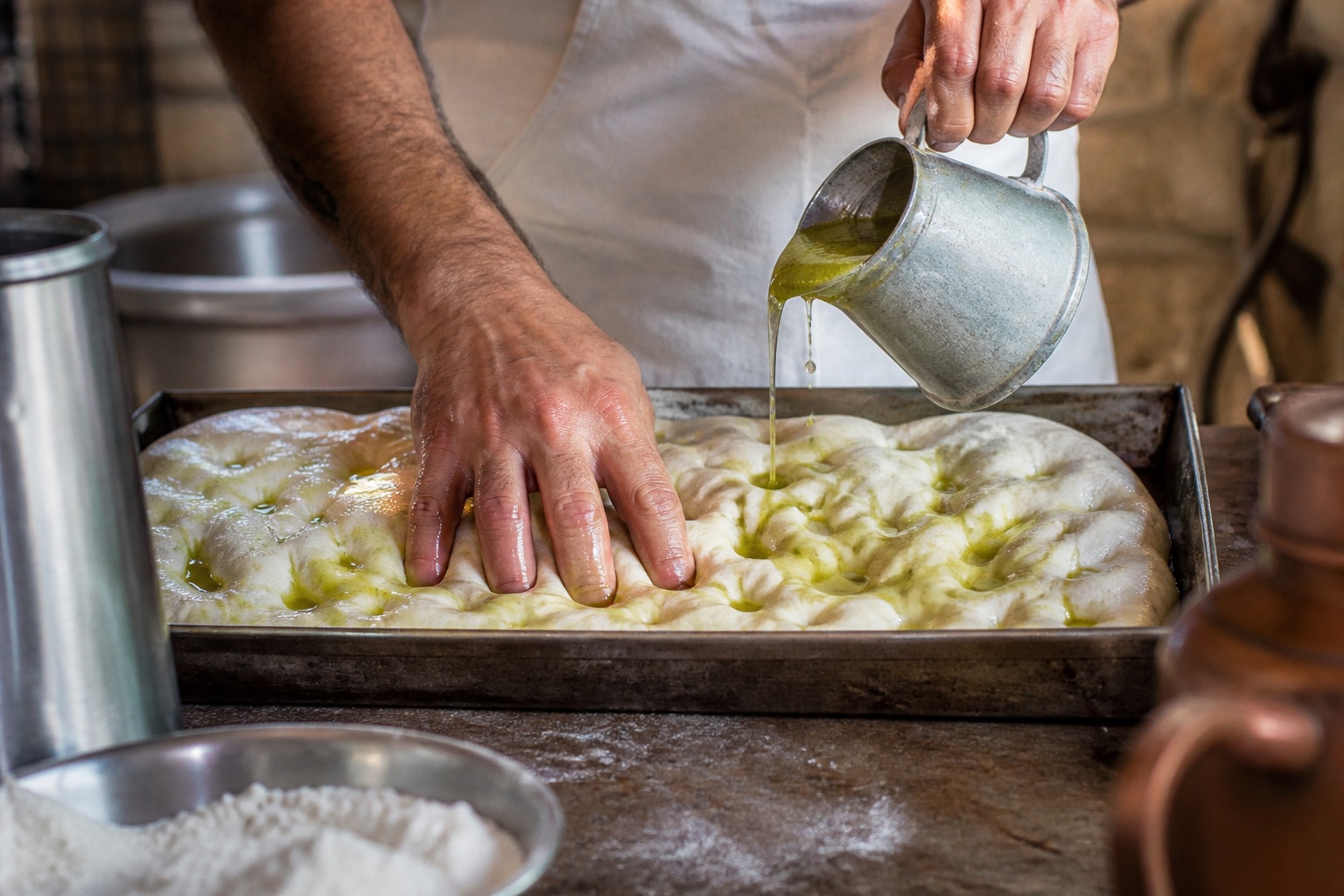Focaccia hamuruna parmak uçlarıyla çukur açılması ve zeytinyağı emülsiyonu